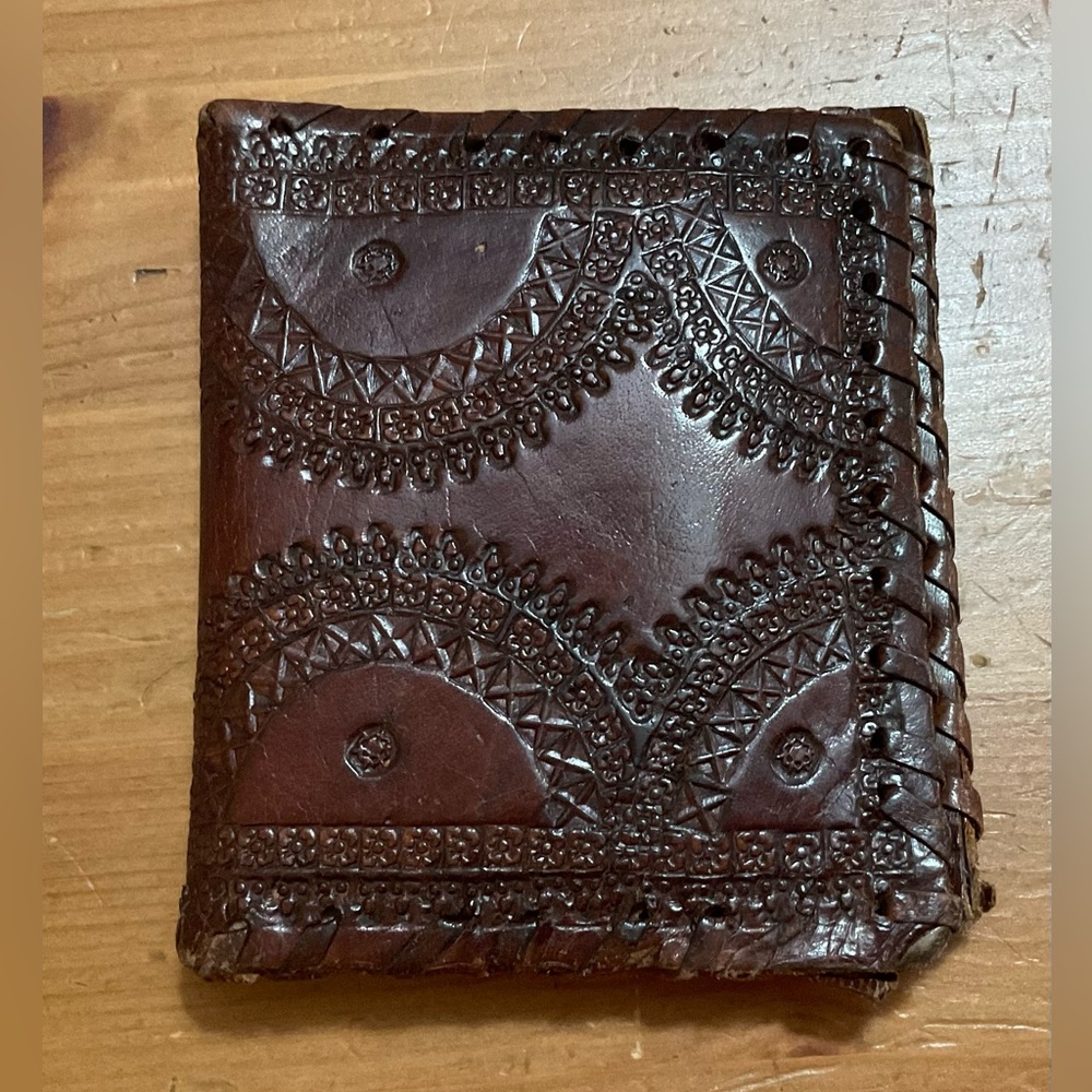 Hand crafted tooled mens leather design bifold wallet laced stitching around it.